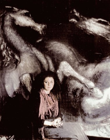 The artist seated in front of a monumental Allegory painting of horses in dark tones.